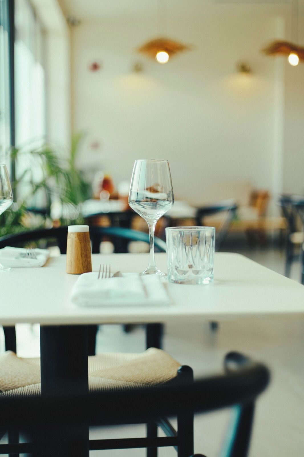 A dining table set with a wine glass, a glass of water, and a wooden salt shaker.
