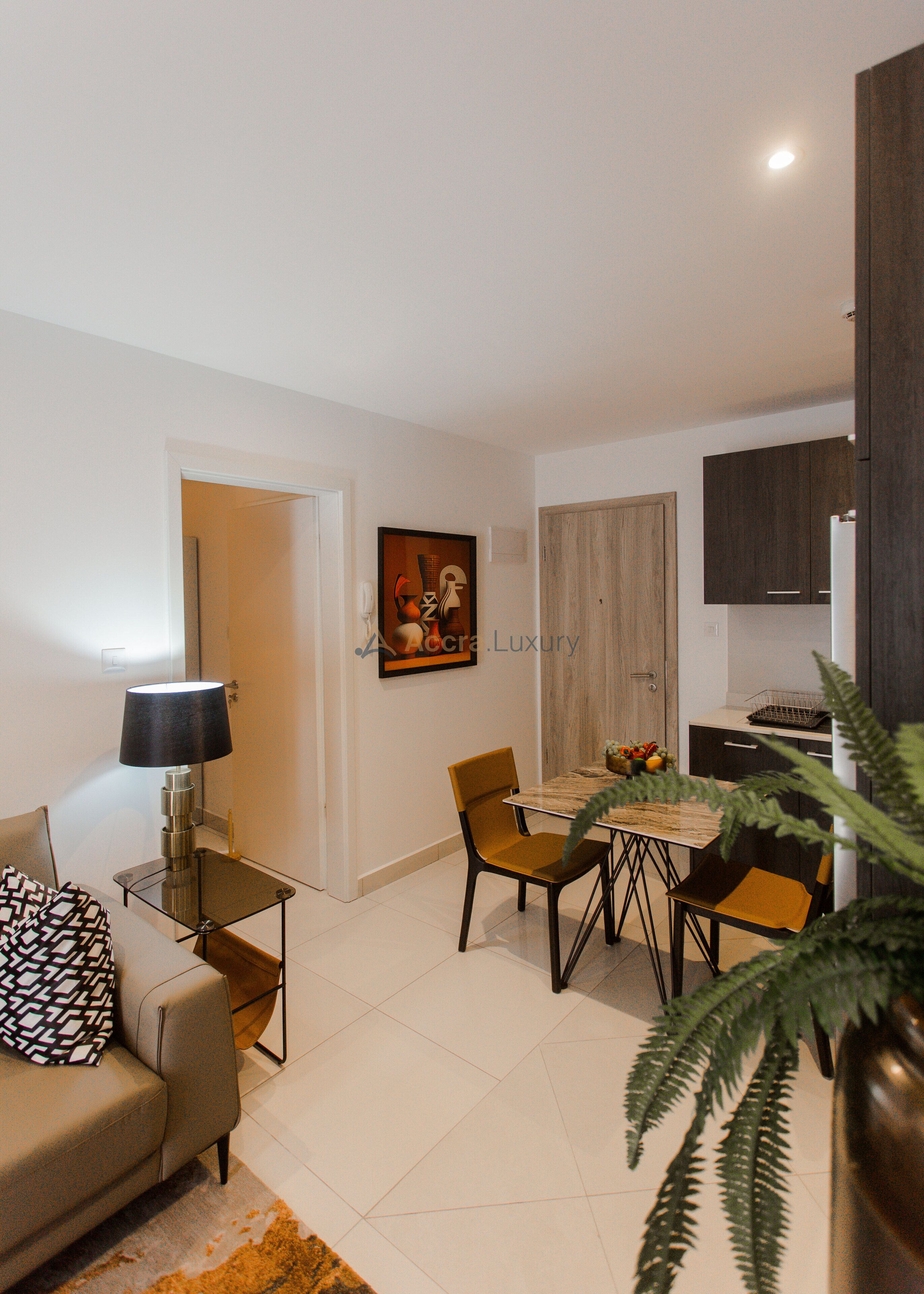 Un salon moderne avec un canapé, une table à manger et des chaises, une lampe et un tableau au mur.