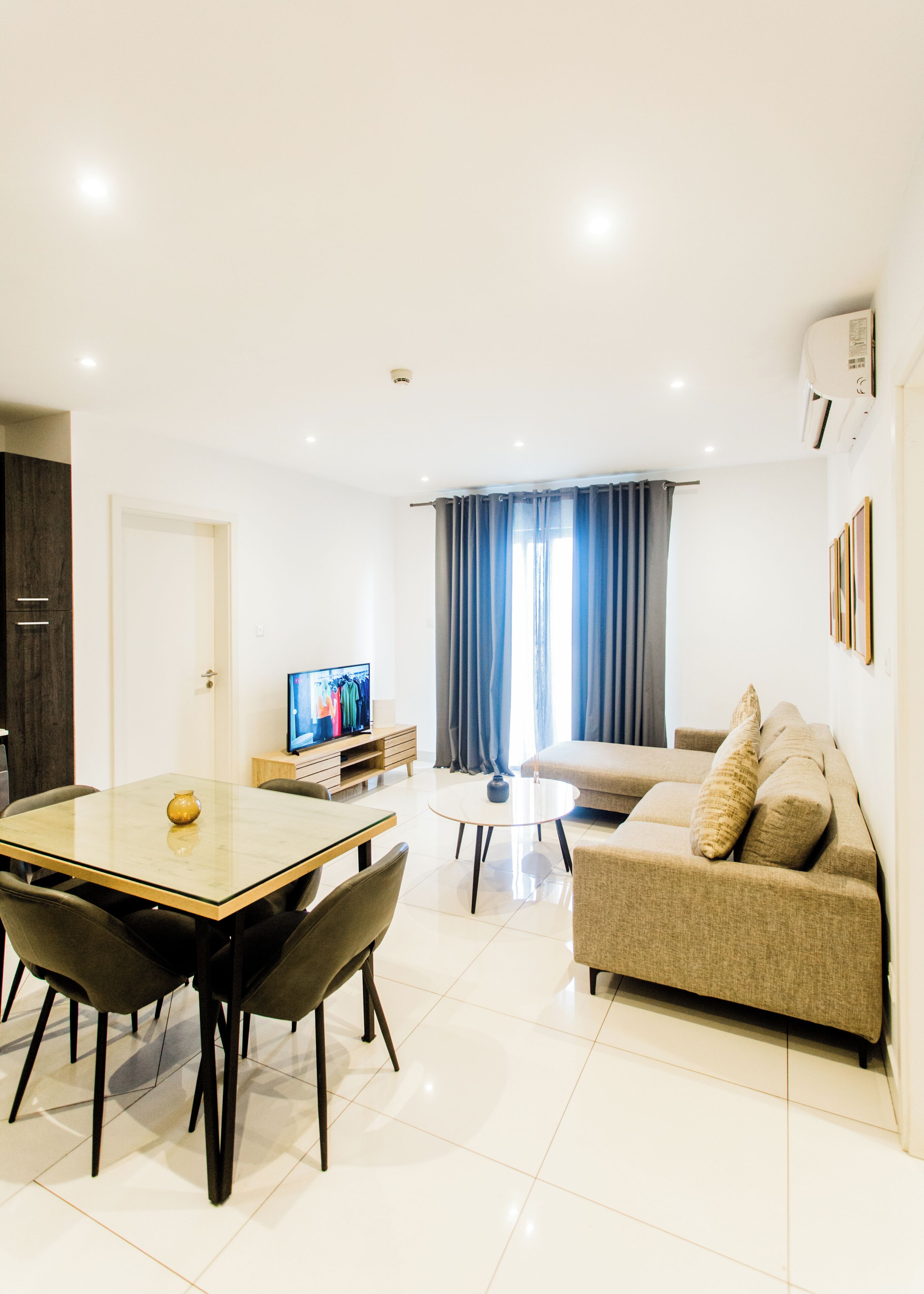 A modern living room with a dining table, sofa, and television.