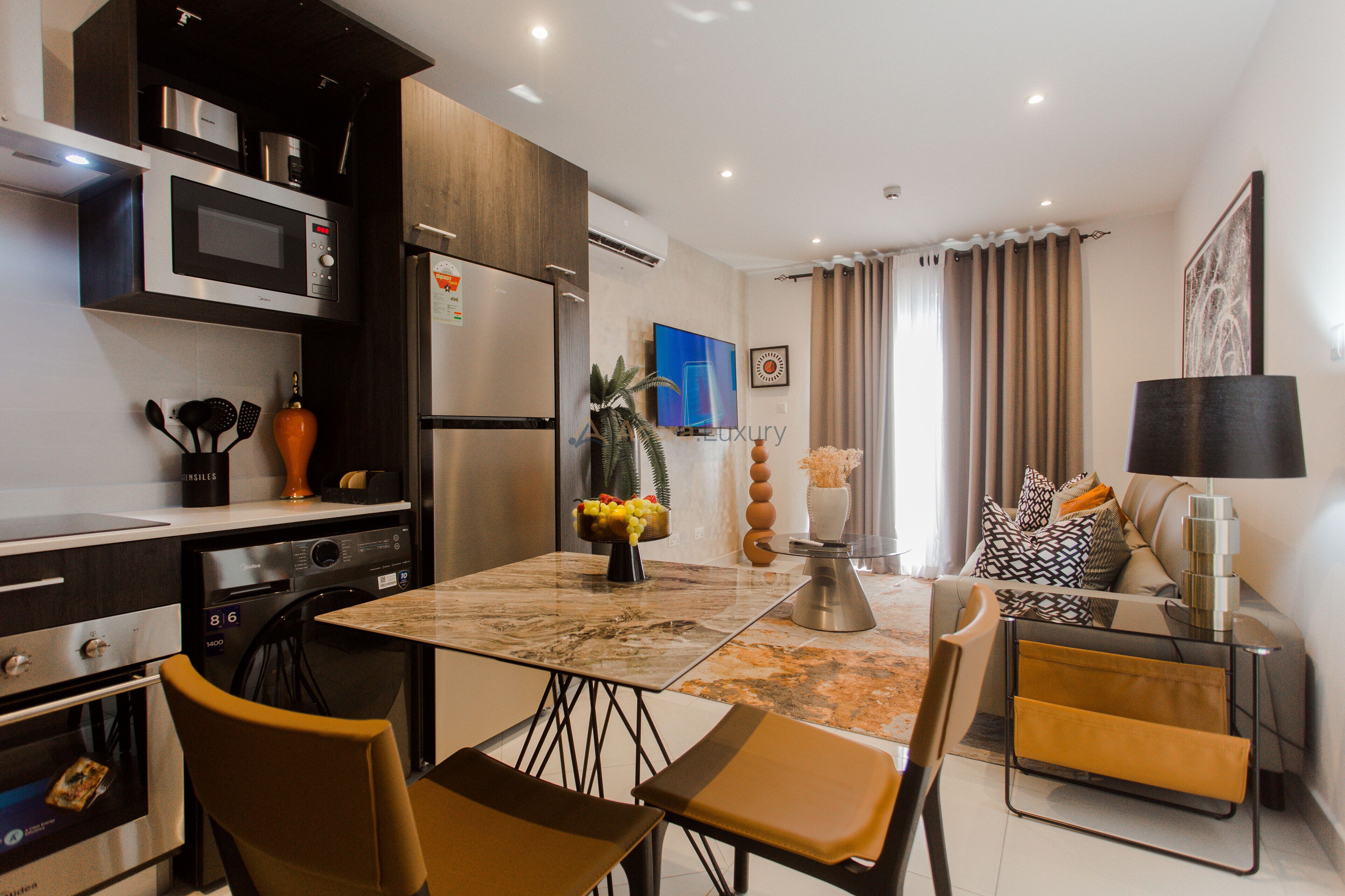 A modern kitchen with a microwave, refrigerator, and dining area with chairs and a table.
