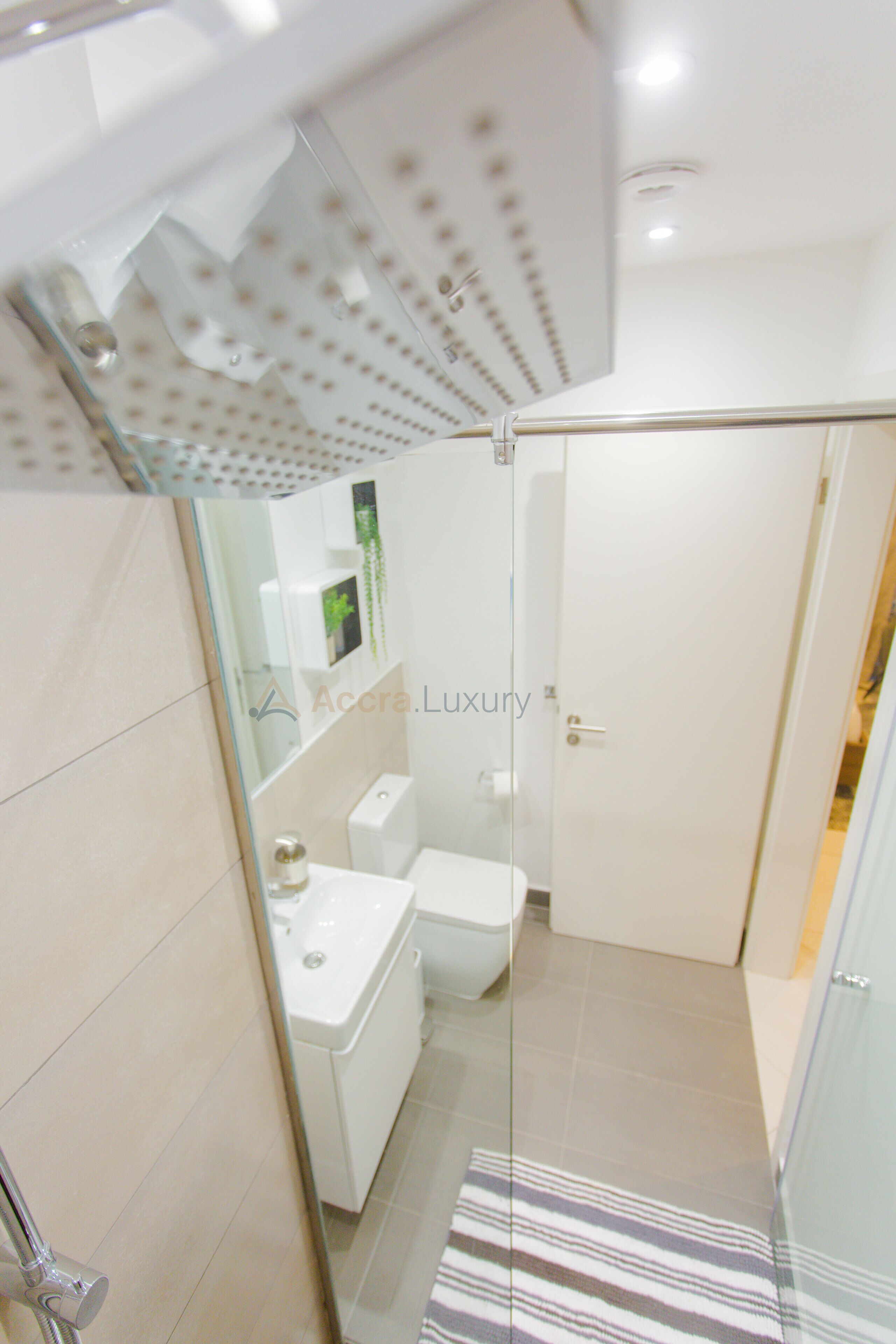 Une salle de bain moderne avec une douche à parois de verre, un lavabo blanc et des toilettes.