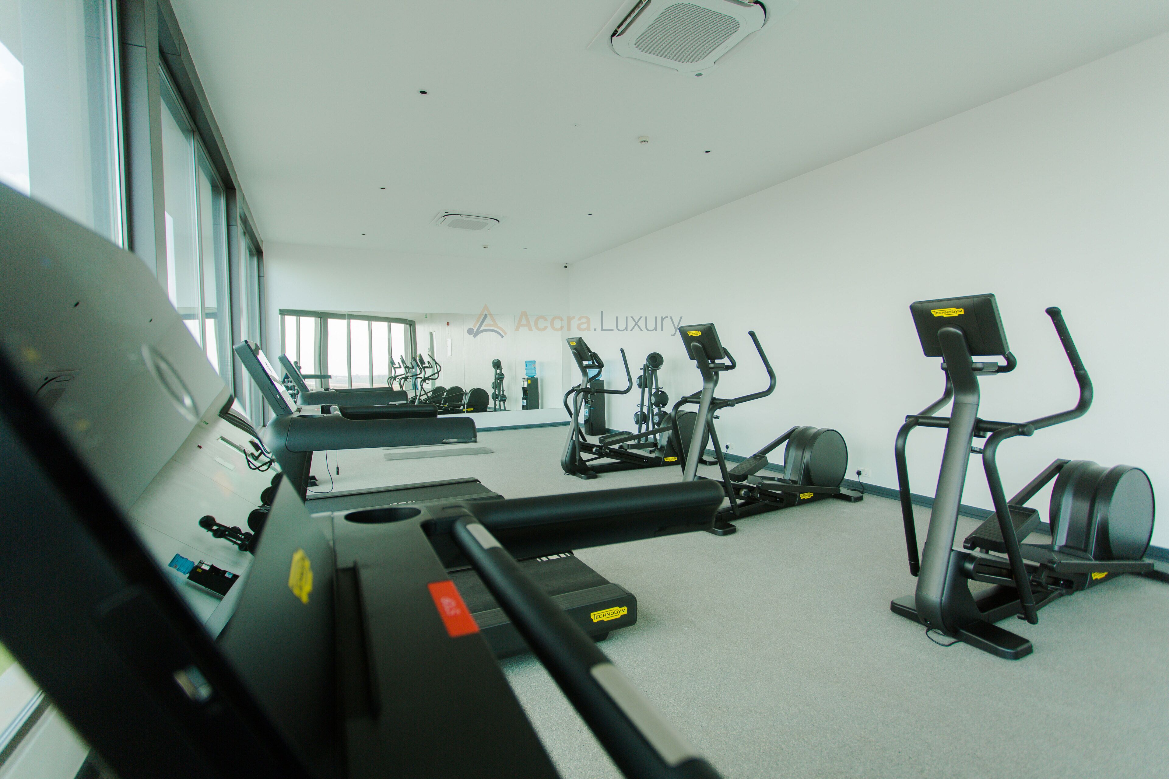 Une salle de sport équipée de divers appareils d’exercice, d ’un tapis de course et d’un mur recouvert de miroirs.