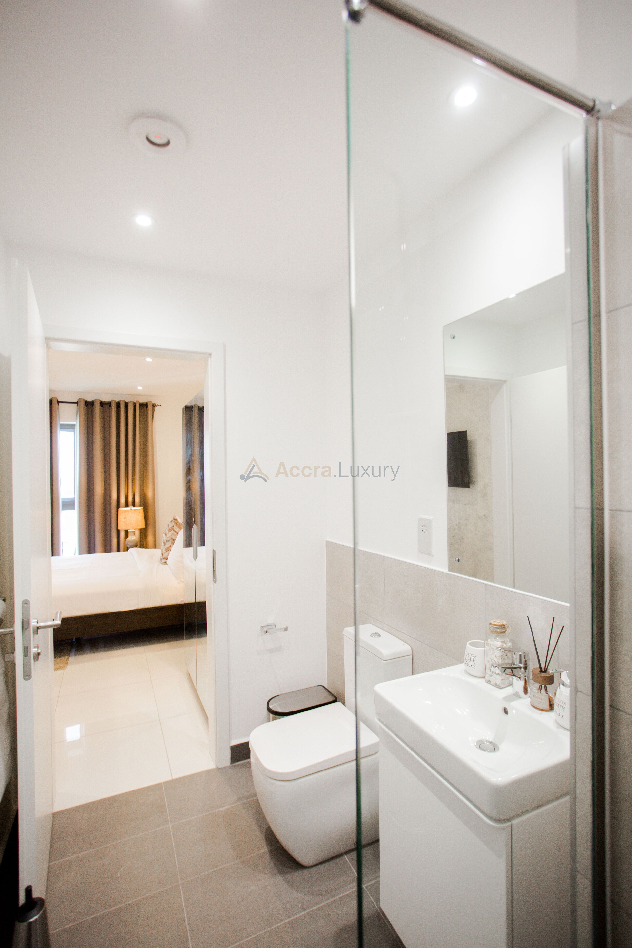 Une salle de bain moderne avec une douche à parois de verre, un lavabo blanc avec un miroir et des toilettes.