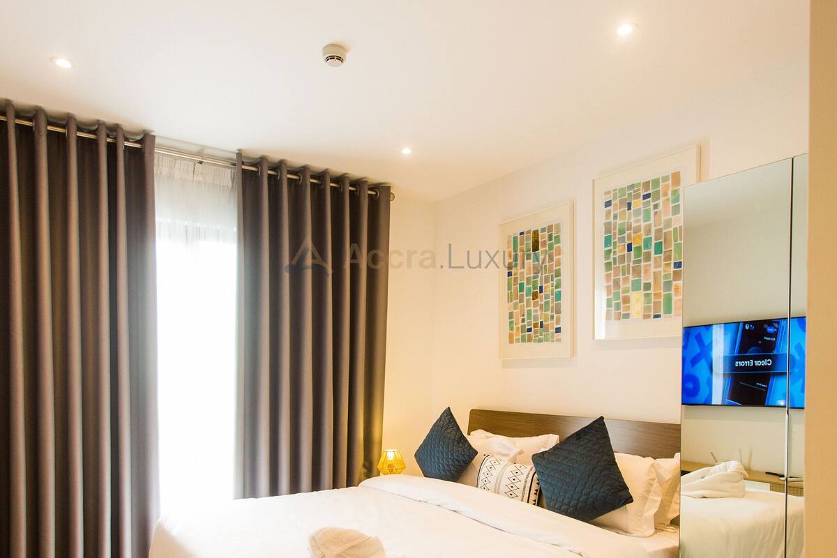 Una habitación de hotel moderna con una cama grande, un televisor de pantalla plana y un espejo de baño.