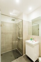 A modern bathroom with a glass-enclosed shower, a white sink, and a large mirror.
