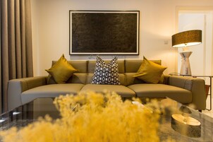 A modern living room with a sofa, decorative pillows, a large abstract painting, and a floor lamp.