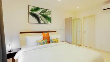 Une chambre d’hôtel avec un lit soigneusement fait, un grand miroir et une œuvre d’art encadrée accrochée au mur.