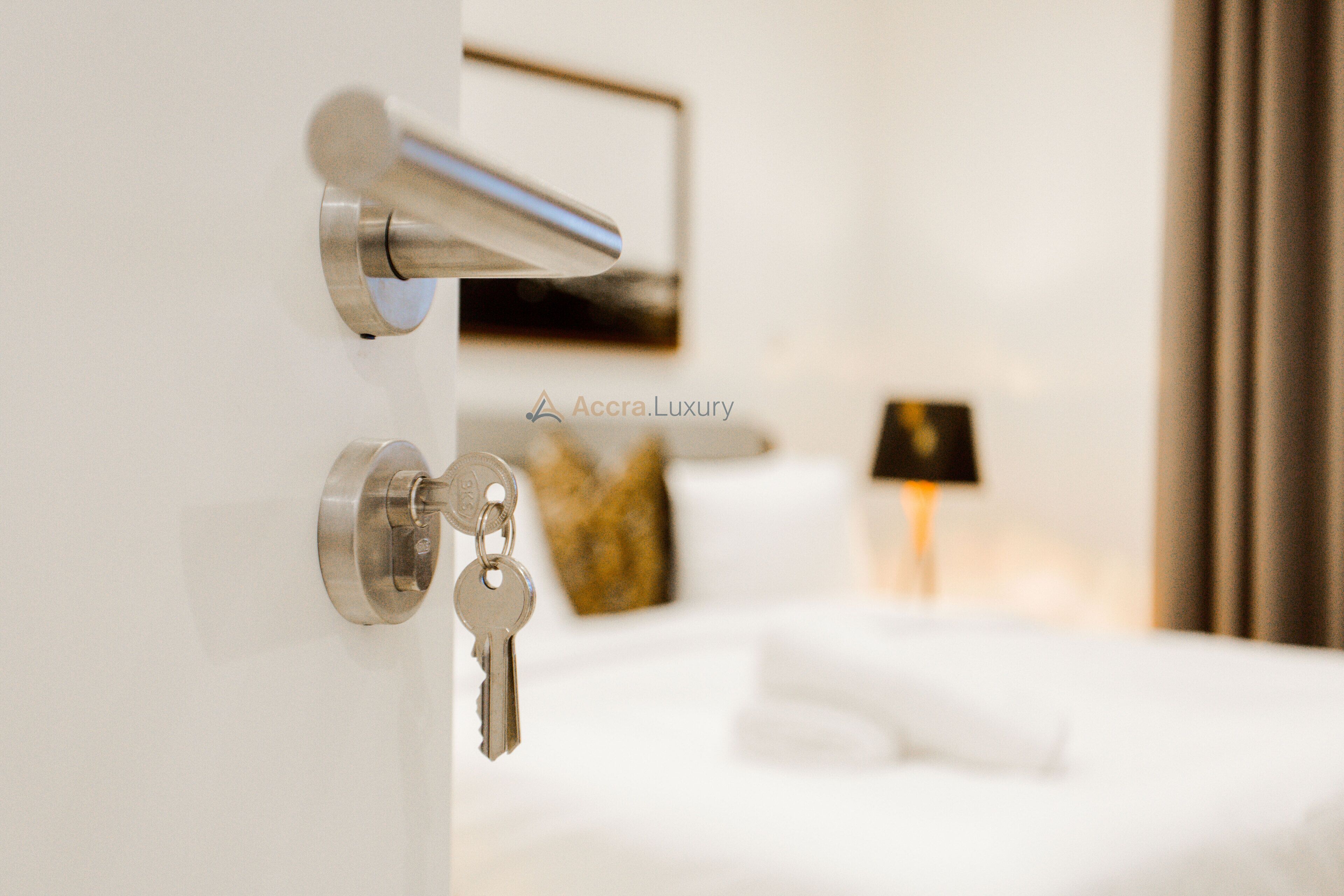A hotel room with a bed, a lamp, and a door with a key.