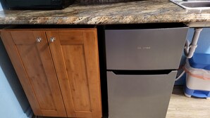 Eine Küche mit Holzausbau, einem Edelstahlkühlschrank und einer Arbeitsplatte aus Granit.