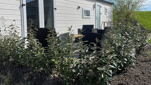 A mobile home with a patio area, outdoor furniture, and a garden.