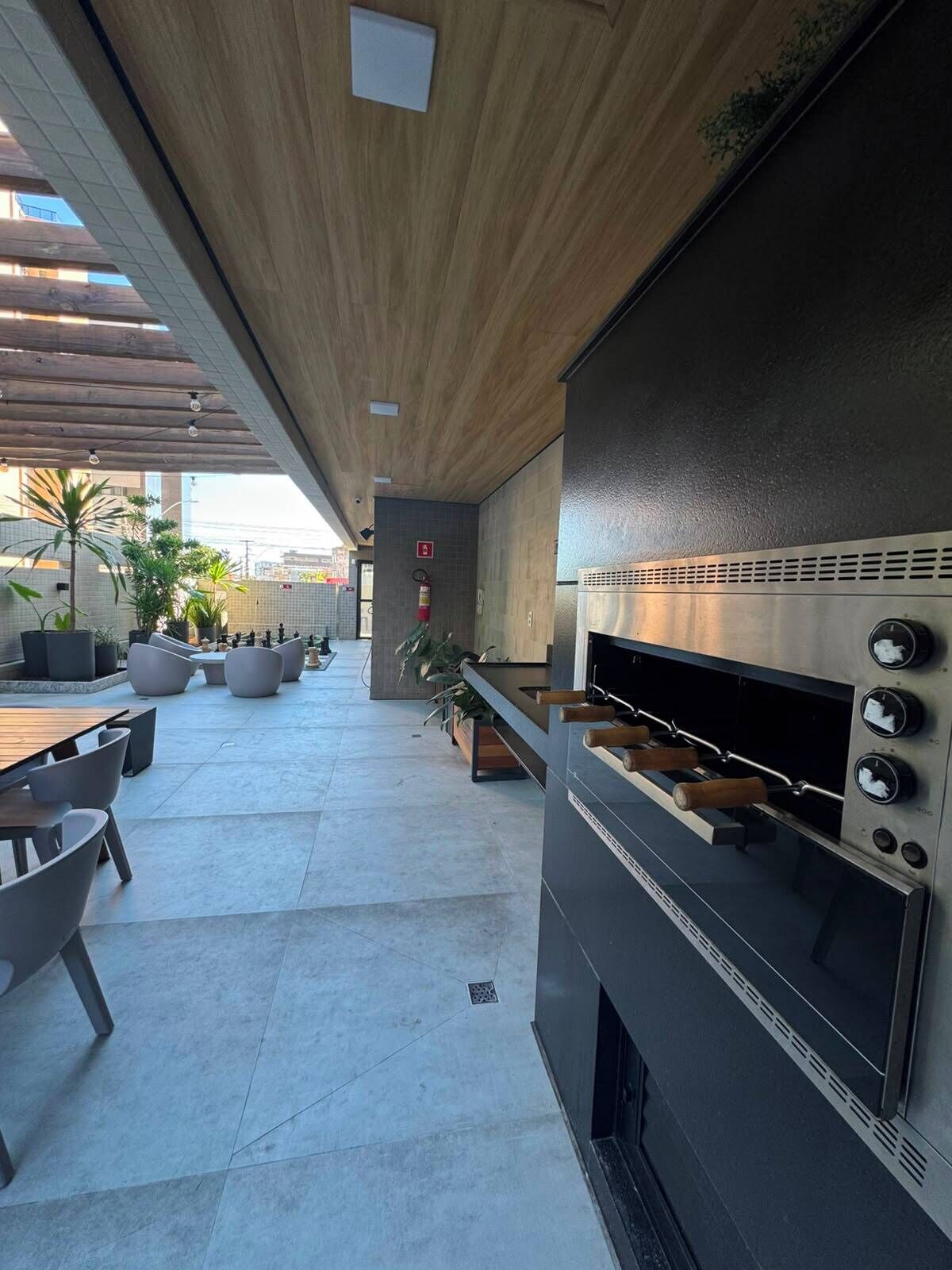 An outdoor patio area with a modern barbecue grill, seating arrangements, and potted plants.