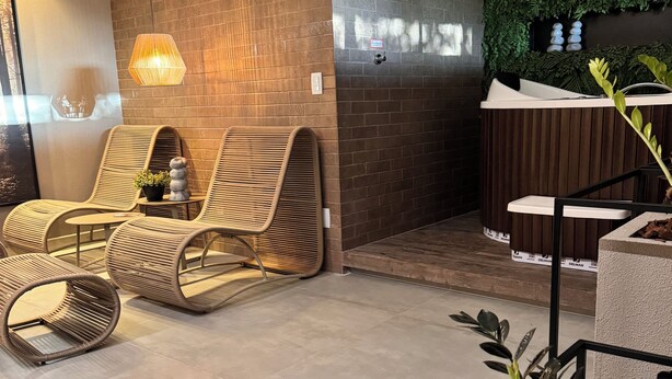 Un espace spa moderne doté de fauteuils de relaxation en osier, d’un plancher chauffant, d’une douche à vapeur murale et d’un mur végétal.