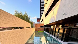 Un espace piscine doté d’un sol carrelé, de chaises longues et d’un tapis flottant.
