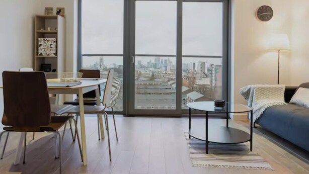Un appartement moderne avec vue sur la ville, comprenant un coin repas, une petite table, un canapé et une bibliothèque.
