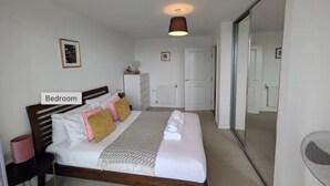 Une chambre à coucher comprenant un lit, une table de chevet, une commode et un miroir.