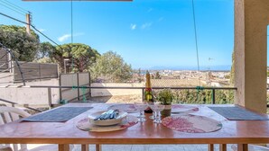 A balcony with a table set for dining, overlooking a cityscape. - House in Roses With Pool Near La Punta Beach (Roses)