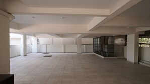 An interior space with a tiled floor, white walls, and a high ceiling with exposed beams. - VISTA LIVING (Kasavanahalli)