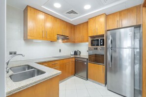 A modern kitchen with wooden cabinets, stainless steel appliances, and a granite countertop. - Premium 2 Bedroom in Trident Residence JBR (Dubai)