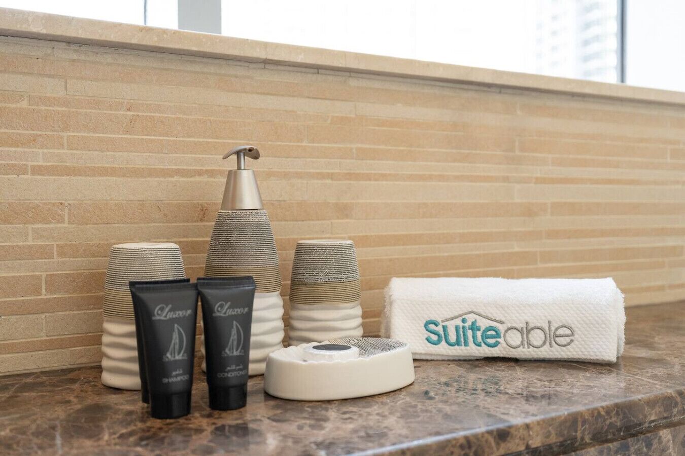 Toiletries on a marble counter with a brick wall background.