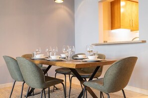 Comedor con una mesa de madera dispuesta para cuatro personas, rodeada por cuatro sillas tapizadas de gris.