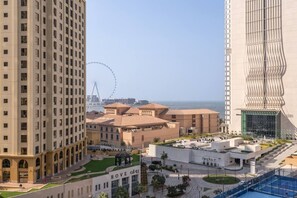 Hotel com pátio central, roda-gigante ao fundo e vista para o mar.