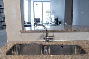 Una cocina con pileta de acero inoxidable, encimera de granito y un espejo grande sobre la pileta.