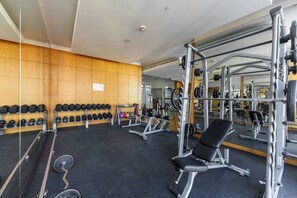 A gym with weightlifting equipment, benches, and a mirrored wall.