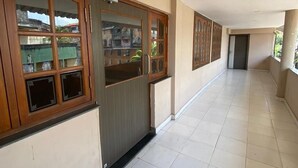 A corridor with tiled flooring, wooden-framed windows, and a door. - Vihasta Sunrise Hotel by RR Enterprises (Margao)