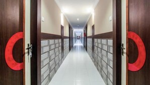 A hotel corridor with wooden doors and tiled walls, leading to a bright hallway. - Vihasta Sunrise Hotel by RR Enterprises (Margao)