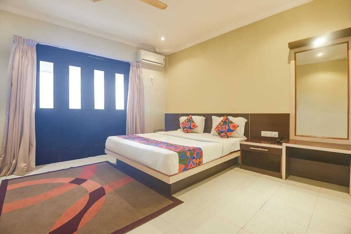 Quarto de hotel com cama, mesa de cabeceira e um espelho grande.