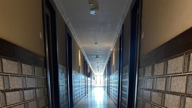 A long, narrow hallway with tiled floors and walls, leading to a bright exit at the end. - Vihasta Sunrise Hotel by RR Enterprises (Margao)