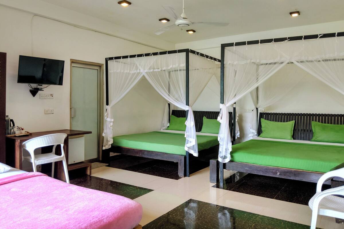 A hotel room with two beds, a TV, a desk, and a chair.