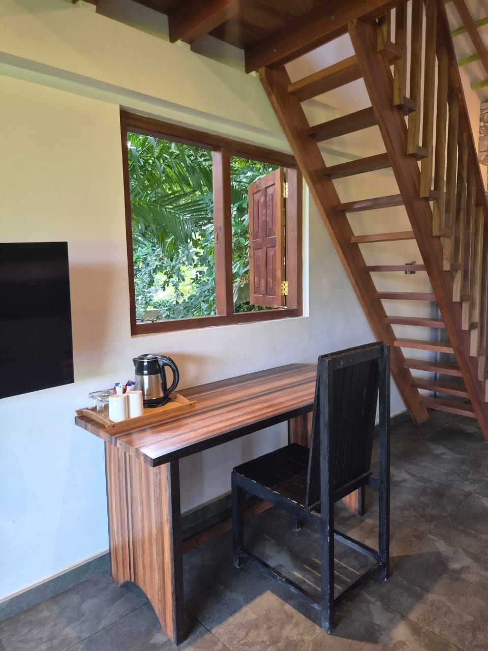 A room with a desk, chair, and a wooden staircase.
