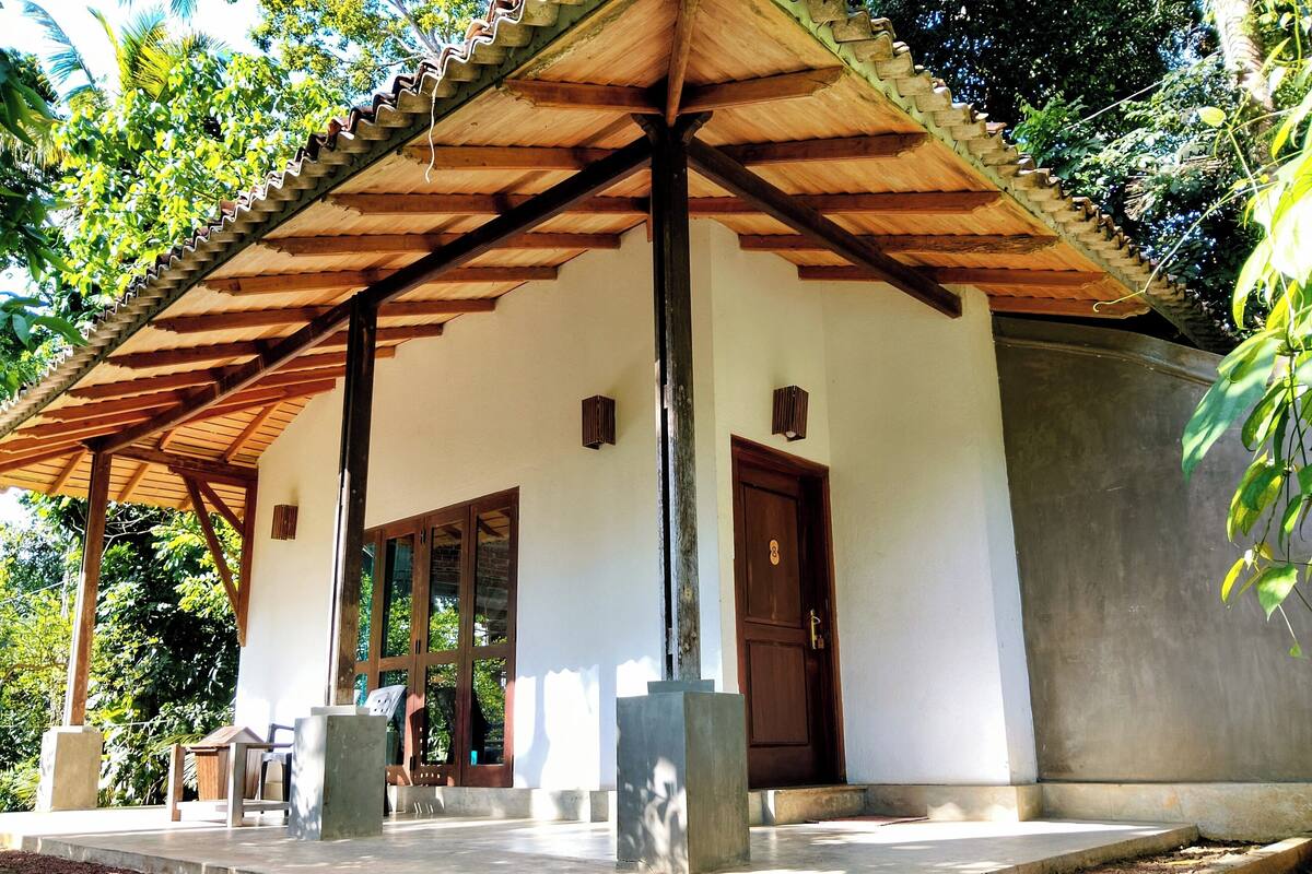 A covered outdoor area with a wooden roof, a door, and a bench.