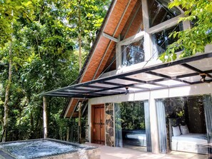 A modern house with a glass-enclosed patio, a hot tub, and a bed visible through the glass. - Leisure Land Villas (SP)