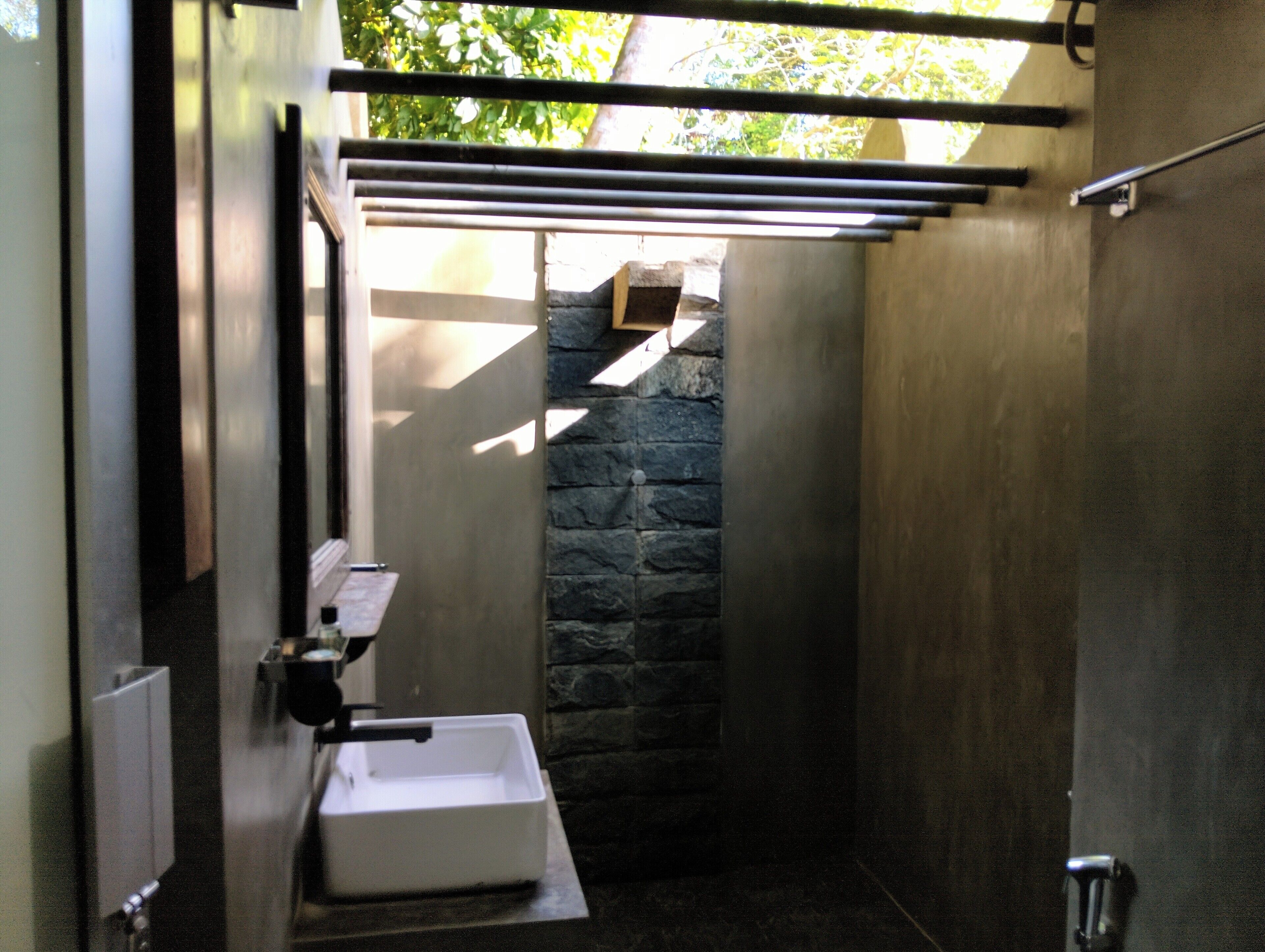 A modern bathroom with a stone wall, a white sink, and a towel rack.
