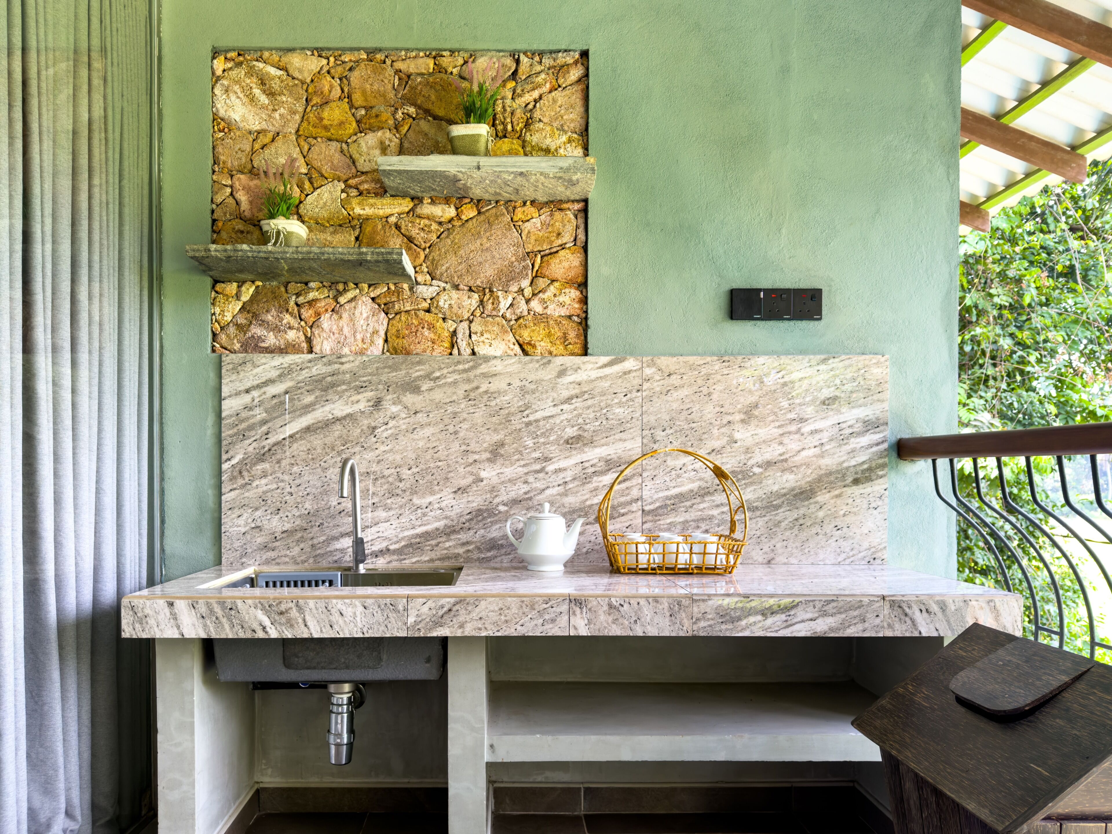 A kitchen with a stone wall, marble countertop, and a basket.