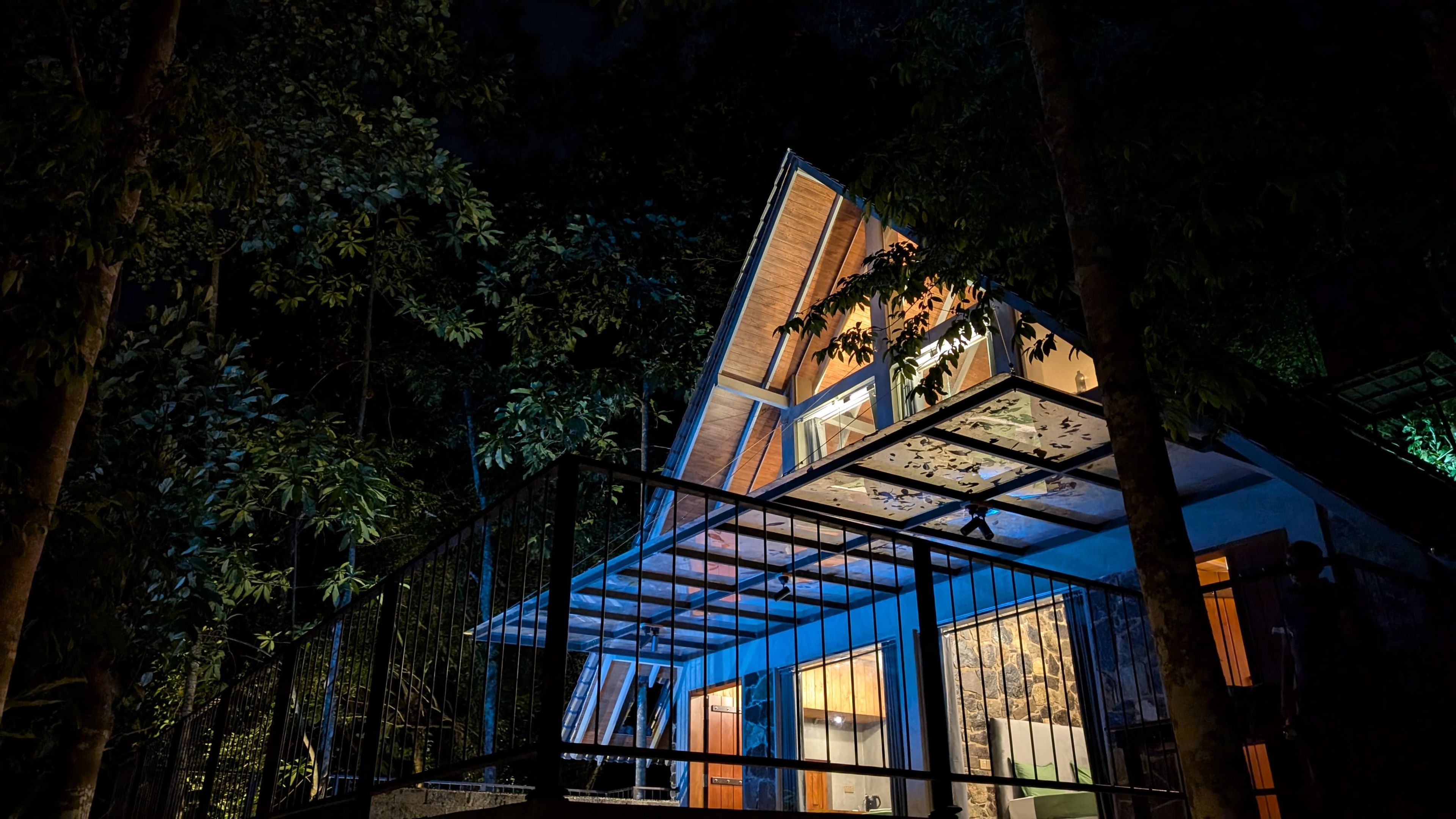 Une structure moderne à plusieurs niveaux, dotée d’une façade en verre et entourée d’une végétation luxuriante.