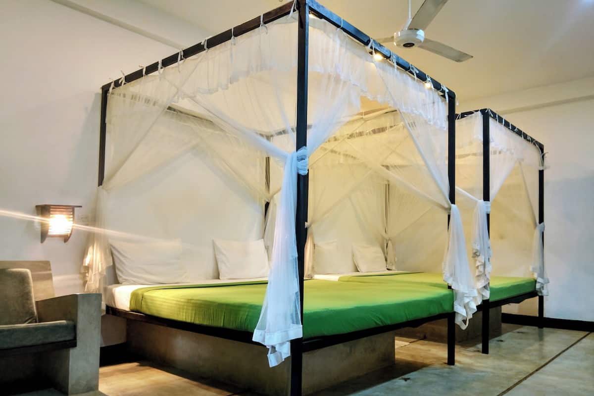 A four-poster canopy bed with white bedding, a nightstand, and a wall-mounted lamp.