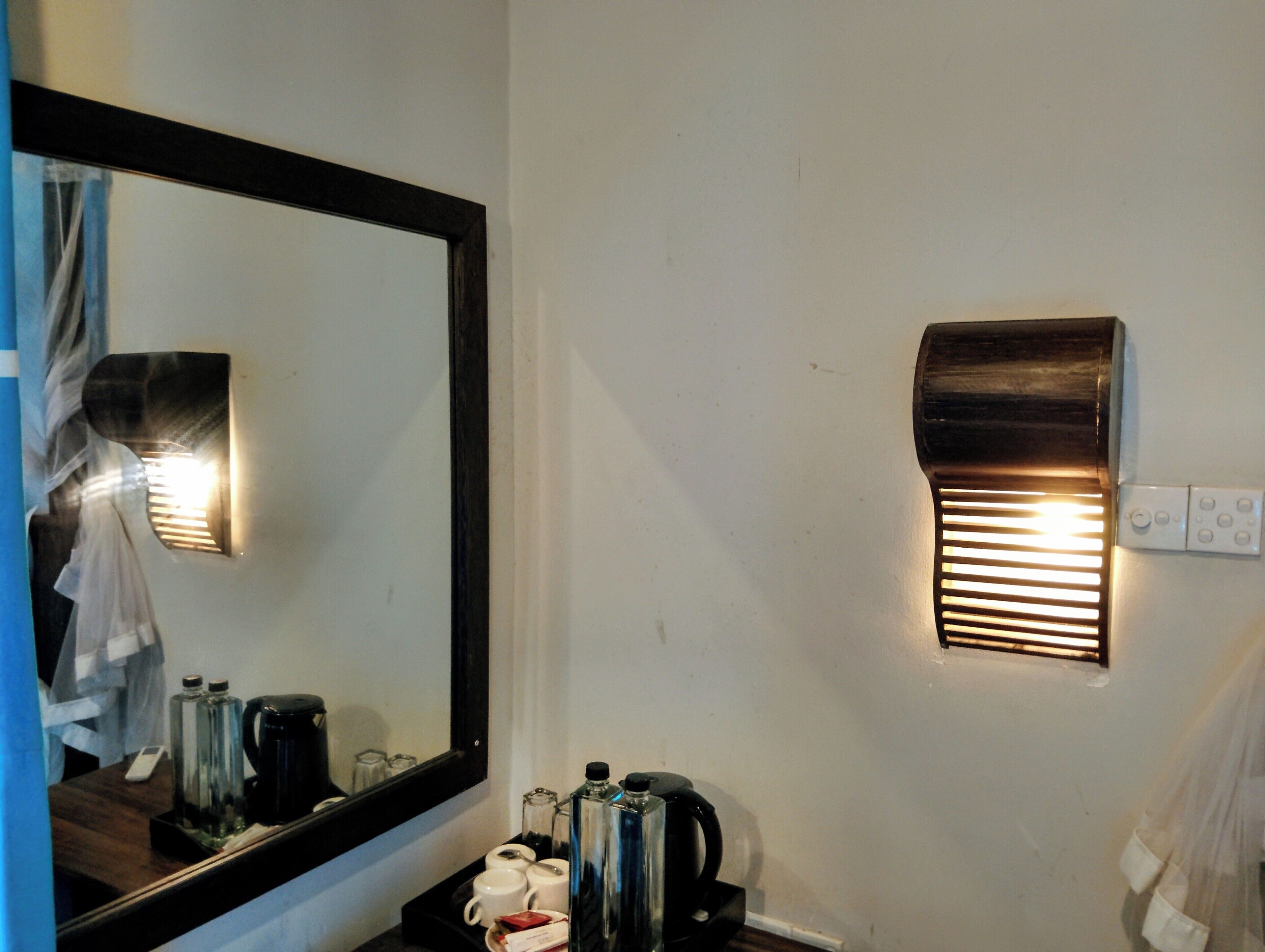 Una habitación de hotel con un espejo grande, un calentador de pared y una bandeja con artículos de aseo.