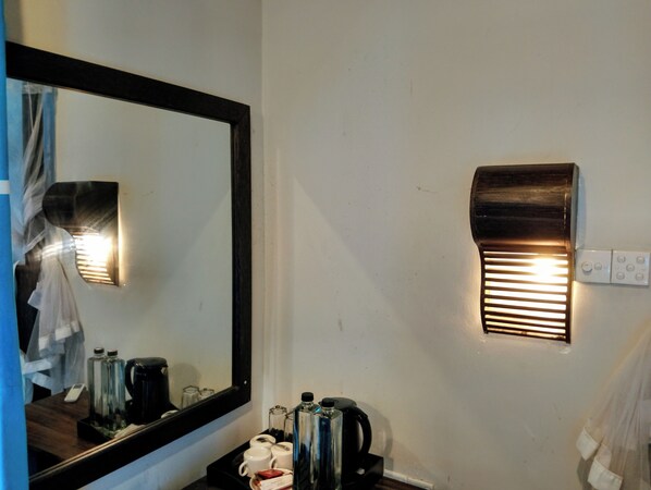 Une chambre d’hôtel avec un grand miroir, un radiateur fixé au mur et un plateau contenant des articles de toilette.