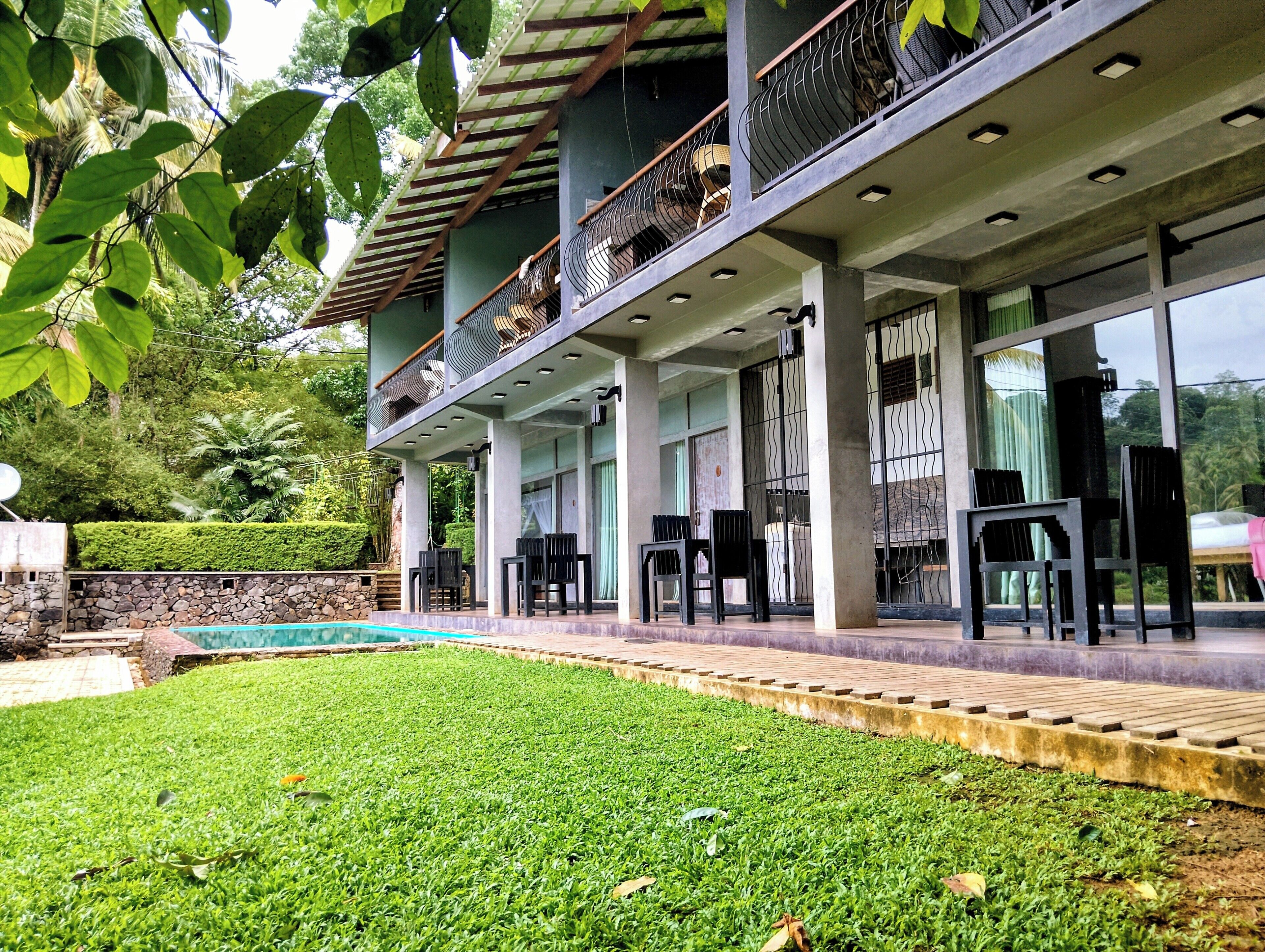 A modern building with a covered outdoor area, a swimming pool, and outdoor seating.