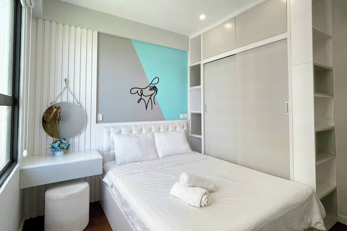 A modern bedroom with a bed, a desk, and a wardrobe.