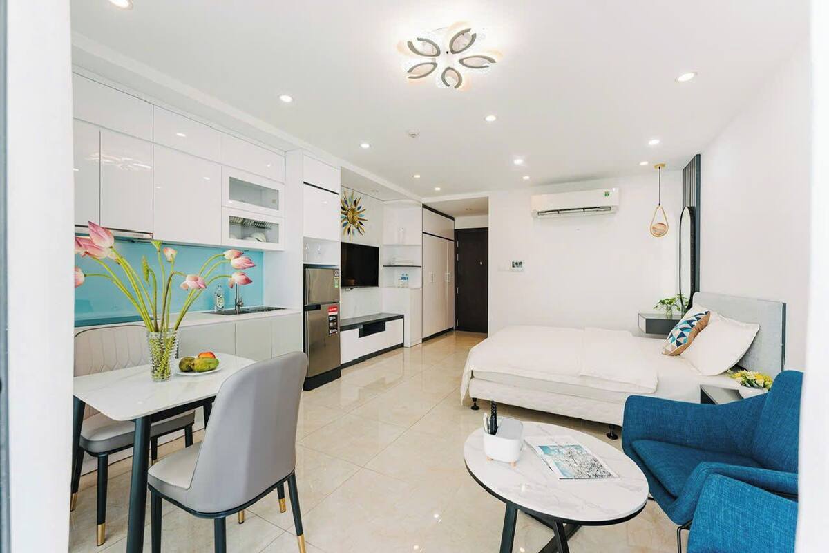 A modern, well-lit room with a dining table, chairs, a sofa, and a bed.
