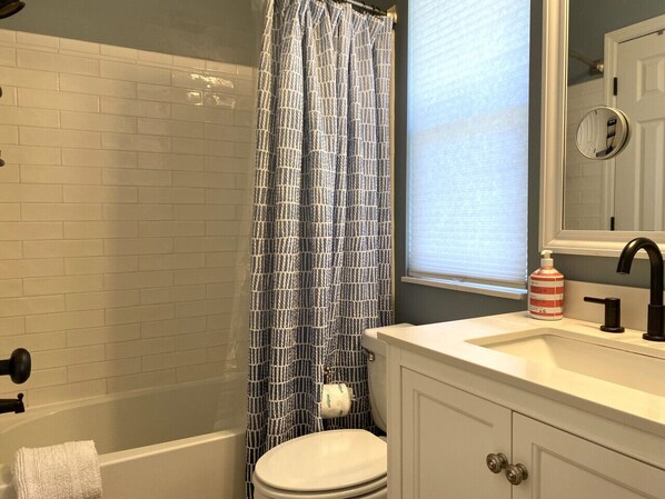 A bathroom with a white bathtub, a toilet, and a sink with a mirror above it. - 26 Davis Love - Cozy Cottage - Owner Cart Incl (Fripp Island)
