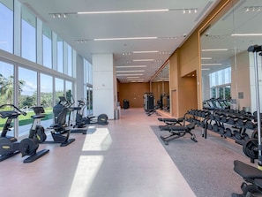 Une salle de sport moderne équipée de machines de cardio, de bancs de musculation et d’haltères.