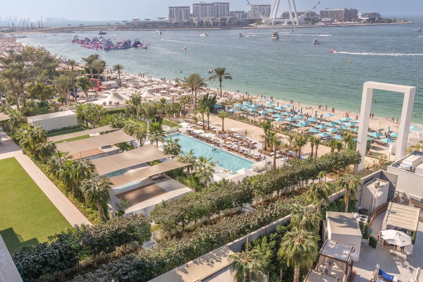 A resort with a swimming pool, beach area, and a view of the sea and a bridge.