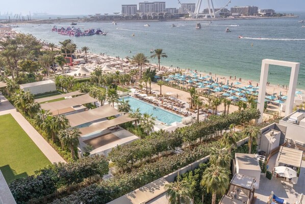 A resort with a swimming pool, beach area, and a view of the sea and a bridge.