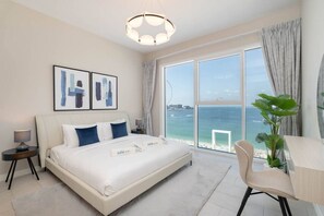 A hotel room with a large bed, a desk, and a view of the ocean.
