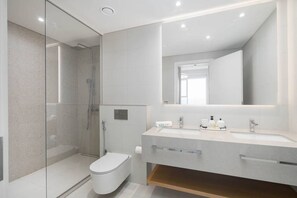 A modern bathroom with a glass-enclosed shower, a toilet, and a vanity with a mirror and sink.